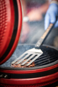 Grilling a steak using direct heat on a red Kamado grill